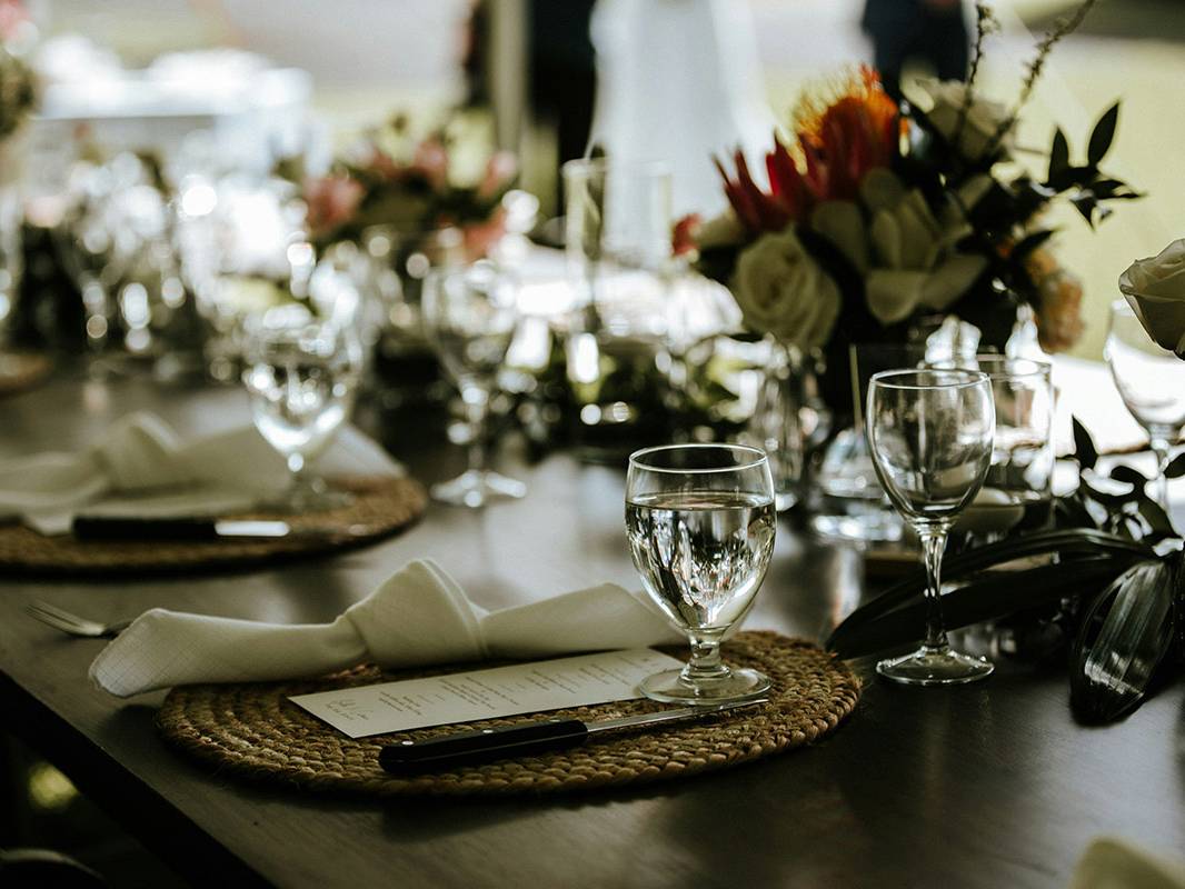 Mesa elegantemente decorada con copas, flores frescas y menús individuales para un evento formal
